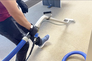 A technician using a steam extraction machine to clean office carpets