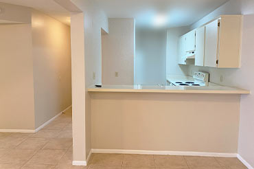 View of the entryway and kitchen in a vacant apartment after cleaning.