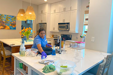 An employee cleaning a kitchen as part of a residential cleaning service