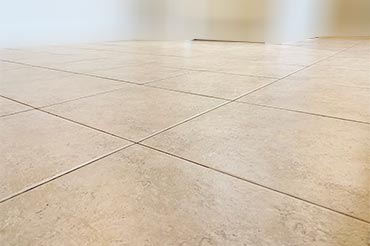 Tile floor being cleaned with a steam machine, removing dirt from tiles and grout