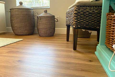 Clean hardwood floor in a living room with a chair, baskets, and a bright window